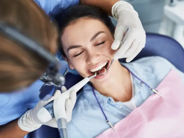 Regular Dental Cleanings: Dentist performing a routine dental cleaning and examination on a patient.
